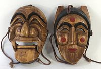 Front view of both masks showing detailed painted features and carved wood texture