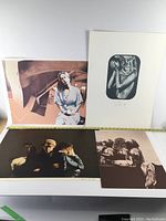 Four surrealist lithographs arranged on a white surface showing varied surreal imagery including portraits and abstract motifs.