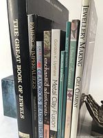Side view showing all nine vintage books stacked vertically with titles visible, including The Great Book of Jewels, Faberge Imperial Eggs, and Jewellery Making.