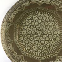Close-up photo showcasing the intricate Islamic geometric and floral pattern etched into the brass tray surface.