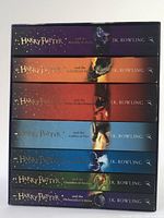 Spine view of all seven Harry Potter books in slipcase showing title, author and color coded artwork for each book.