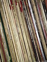 Spine view of vintage vinyl LP records showing titles, tape labels from a radio station, and wear on sleeves.