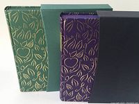 Front view of two decorative hardcover books with gold embossing and slipcases