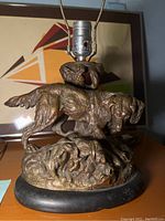 Full view of dog sculpture lamp atop stone base with lamp fixture on top.