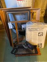 Wooden frames stacked behind Craftsman miter box, Dollhouse kit standing upright