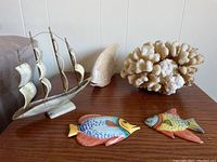 Full lot view showing model ship, coral piece, carved stone fish, and two hand-painted decorative fish