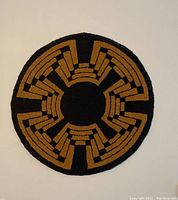 Top-down view of the round rug with black and mustard geometric pattern.