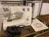 Full view of Kenmore sewing machine with foot pedal and owner's manual on a wooden surface.