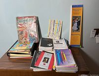 Full overview of collection with Ms. magazines in plastic, theater playbills stacked, Annual Mammoth Book of Fairytales on table next to tall Renoir calendar