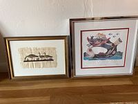 Two framed prints displayed side by side on wooden floor against white wall. Left print shows geese motif on papyrus, right print shows Jonah and the Whale scene numbered 146/300.