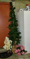 Full view of the tall Christmas tree, vintage Santa figurine, and pink poinsettias arranged together.