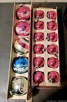Two boxes of vintage glass Christmas ornaments, one containing five large colored ornaments with mica designs and painted holiday scenes, the other with fourteen smaller shiny pink ornaments.