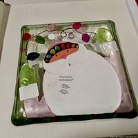 Back side of the square glass Christmas plate showing artist and brand information.