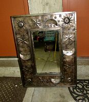 Front view of the large rectangular mirror with metal frame showing raised sun, moon, and star designs