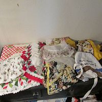 Photo showing assorted Christmas napkins and vintage aprons laid out on a surface.