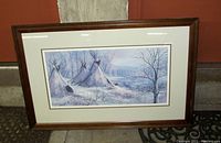 Photo of framed picture showing indigenous village tepees in a snowy winter setting, measuring about 32.5" x 21.5". Taken to document condition and framing.