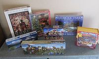 Overview of all seven sealed puzzle boxes showing title, piece count, and images on boxes.