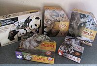Photo shows six puzzle boxes arranged on a surface, highlighting the National Geographic Giant Panda puzzle and the 'I Am' series puzzles including Lion, Bison, Sloth, and Owl. All boxes appear new and sealed in plastic.