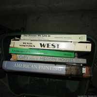 Top view of a stack of five books on a green chair showing titles and dust cover condition.