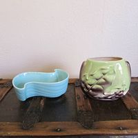 Photo showing a small aqua blue ceramic dish and a green ceramic planter with leaf relief design from the front and side angle.