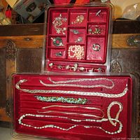 Photo capturing full view of both red velvet trays packed with jewelry showing the overall lot setup.