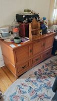Front view of the red cedar hope chest with louver slats, two door handles, and bottom drawer with two pulls. Various items placed on top of the chest.