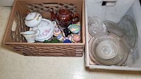 Assorted dishware and teapots packed together in crates, including glass dishes, bowls and various ceramic pieces.