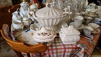 Photo showing the three ironstone tureens on a table surrounded by additional dishware, displaying different sizes and styles and showing the overall collection.