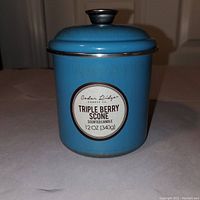 Blue ceramic jar candle labeled Triple Berry Scone with metal lid, unopened and unused.