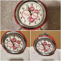 Close-up front and side views of the vintage Coca-Cola bottle cap themed wind-up alarm clock showing red body, chrome edging, and detailed clock face graphics.