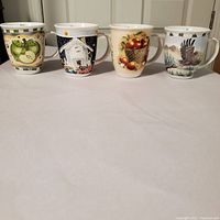 Set of 4 large coffee mugs with different painted designs placed in a row, showing full front views.