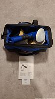 Polisher with white buff pad attached inside open carrying case, instruction manual, and lot tag.