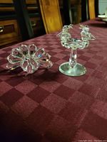 Front view of two crystal figurines on tablecloth, showing birds on birdbath and peacock.