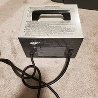 Front view of 24 Volt Lester Dual Mode Automatic Battery Charger with cables and handle visible.