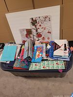 Plastic bin filled with various sized and colored gift bags, including solid colors, holiday patterns, and novelty designs