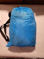 Blue inflatable lounger packed inside a blue nylon storage bag with black shoulder strap