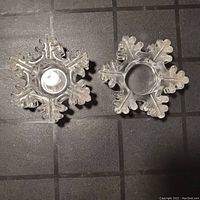 Top view of two clear crystal snowflake tealight holders showing the circular depression for the candle.