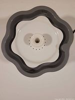 Top-down view of floral shaped pet water fountain showing central spout with water holes.