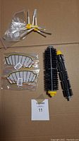 Roomba 500 Series replacement parts displayed on cardboard including side brushes, filters, main brush, and roller brush.