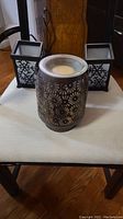 Front view of the Scentsy Daisy warmer and two square Partylite tealight candle holders on a white cloth on chair seat.