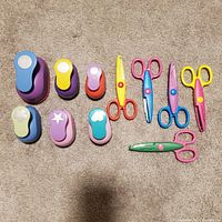 Photo of seven colorful paper punches with different shapes and six illustrated scissors
