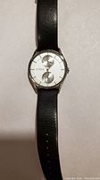 Front view of Skagen watch showing silver dial with two subdials and black leather strap laid flat