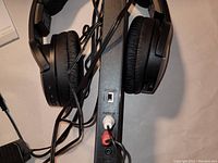 Sony wireless padded headphones hanging on the transmitter base with cables connected.