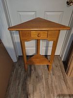 Front view of solid pine wooden triangle corner table with small drawer and two shelves