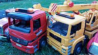 Side view showing red Bruder Mercedes Actros truck and yellow Bruder MAN TGS crane truck