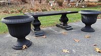 Bench and planters positioned on paved surface outdoors, showing full front view