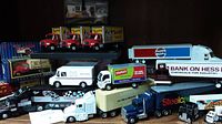 Full view of multiple die cast advertising semi trucks arranged on shelf, showcasing brands including Pepsi, Hess, Staples, Steelcase, and Goodwrench. Various colors and sizes visible with detail and branding.