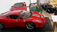 Front angle displaying 4 Ferrari model cars in red, green, and black, showing scale and details