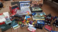 Photo showing assortment of board games, toys including dancing duck, robot figures, collectible cars, marbles, and other items.