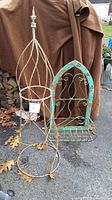Full view of rustic metal garden topiary and planter side by side, showing structure and patina.